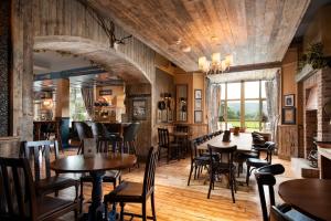 un restaurante con suelo de madera, mesas y sillas en The Coniston Inn - The Inn Collection Group, en Coniston