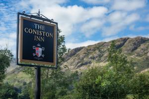 una señal para la posada confusa con montañas en el fondo en The Coniston Inn - The Inn Collection Group, en Coniston