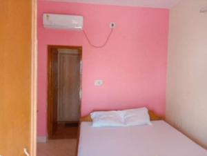 a bedroom with a pink wall and a white bed at Green Valley Hotel and Resort- Resort in Mandarmoni