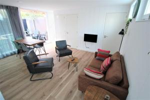 een woonkamer met een bank, stoelen en een tafel bij Beaufort in Egmond aan Zee