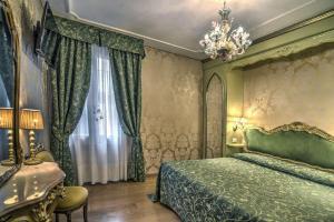 Un dormitorio con una cama verde y una lámpara de araña. en Hotel Bel Sito e Berlino, en Venecia