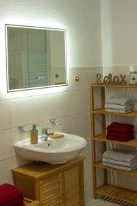 La salle de bains est pourvue d'un lavabo, d'un miroir et de serviettes. dans l'établissement Ferienwohnung FUCHSBAU im EG des Ferienhauses Falkenhöhe, à Meuselbach-Schwarzmühle