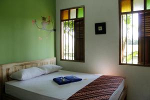 a bed in a room with two pillows and two windows at Omah Kebon Nitiprayan in Bantul