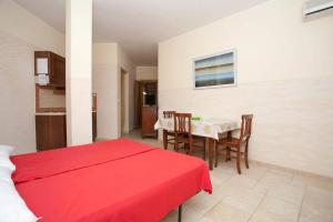 1 dormitorio con cama roja y mesa con sillas en Residence Club Costa D'Oriente, en Torre dell'Orso