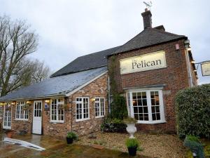 a brick building with a sign that reads the pelican at The Pelican Inn in Froxfield