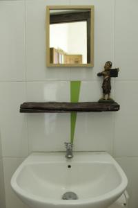 a bathroom with a sink with a mirror and a statue at Omah Kebon Nitiprayan in Bantul