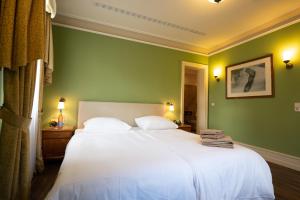 エルトフィレ・アム・ラインにあるResidenz Weingut Schloss Reinhartshausenの緑の壁の白いベッドが備わるベッドルーム1室
