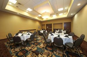 uma sala de conferências com mesas e cadeiras brancas e um ecrã de projecção em Holiday Inn Titusville/Kennedy Space Center, an IHG Hotel em Titusville