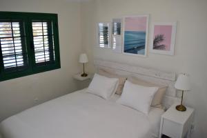 een slaapkamer met een wit bed met witte kussens bij Beachfront Bungalow Cotillo Lagos in Cotillo