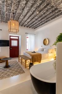 a bedroom with a bed and a table and a tub at The TownHouse Mykonos in Mýkonos City