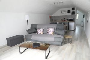 ein Wohnzimmer mit einem grauen Sofa und einem Tisch in der Unterkunft Gîtes La Cigale et Le Grillon in Bouillon