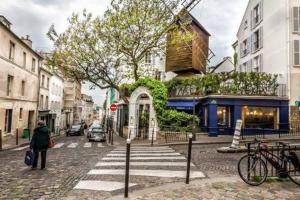 a person standing on a street with a crosswalk at Centre Montmartre, charming and cozy appartement in Paris