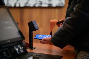 una persona sentada en una mesa con un mando a distancia en citizenM Paris Charles de Gaulle Airport, en Roissy-en-France