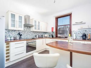 uma cozinha com armários brancos e uma mesa de madeira em Casa Fresa - Ferry House em Broughty Ferry