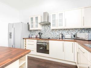 a kitchen with white cabinets and a refrigerator at Casa Fresa - Ferry House in Broughty Ferry