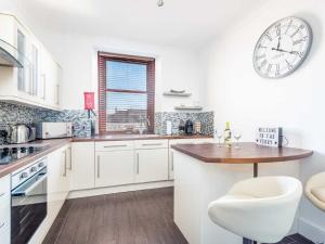 una cocina blanca con un reloj grande en la pared en Casa Fresa - Ferry House, en Broughty Ferry