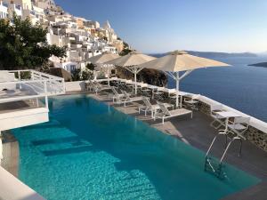 uma piscina com cadeiras e guarda-sóis junto à água em Panorama Suites em Fira