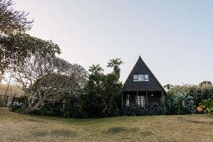 a small house with a black roof on a field at Umzumbe Surf House in Umzumbe