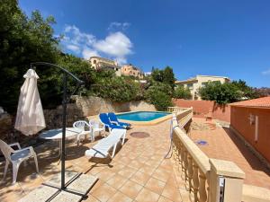 a patio with a pool and chairs and a umbrella at Villa June in Benitachell