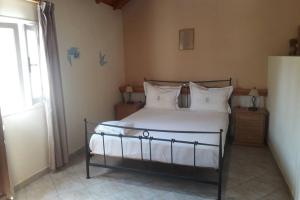a bedroom with a bed with white sheets and a window at AMYGDALIA in Vlachopoulátika