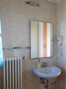 bagno con lavandino, specchio e radiatore di Residence ONDA BLU 2 a Cervia