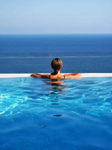 a person sitting in a swimming pool looking out at the ocean at Pagliarulo Complex by AMALFIVACATION in Ravello