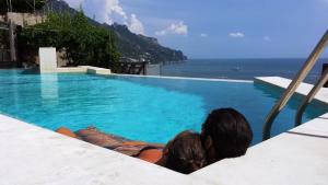 un hombre y una mujer sentados en una piscina mirando al océano en Pagliarulo Complex by AMALFIVACATION, en Ravello