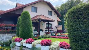 ein Haus mit einem Garten mit Blumen davor in der Unterkunft Apartment Vihor in Zlatibor