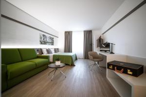 una camera d'albergo con un divano verde e un letto di Bonotto Hotel Palladio a Bassano del Grappa