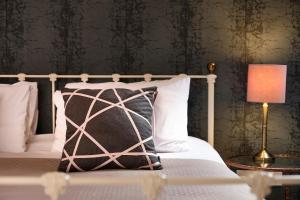 a bed with a black and white pillow and a lamp at The Westleton Crown in Westleton