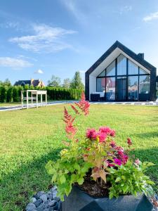 una pequeña casa negra con flores en un patio en HARMONY Design and Vacation House en Bigauņciems