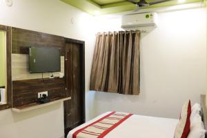 a bedroom with a bed and a tv on the wall at Hotel Sun Shine in Ābu Road