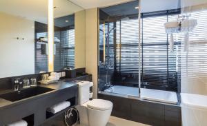 a bathroom with a toilet and a sink and a tub at Holiday Inn Bangkok Sukhumvit, an IHG Hotel in Bangkok