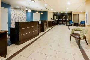 a lobby with a waiting area with a chair and desks at La Quinta by Wyndham Columbus - Grove City in Grove City