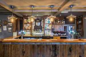 a bar with a wooden counter with bottles of alcohol at The Westleton Crown in Westleton