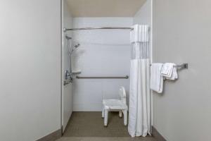 a bathroom with a shower with a toilet and a chair at La Quinta by Wyndham Fairbanks Airport in Fairbanks
