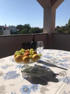 a plate of fruit on a table with a wine glass at Apartment and Room Marlen in Rovinjsko Selo