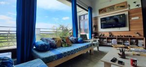 a living room with a blue couch and a large window at IbisHouse Farm Stay in Bharatpur