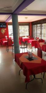 a dining room with red tables and chairs with red tablesearcher at Kyato Hotel in Kasanda