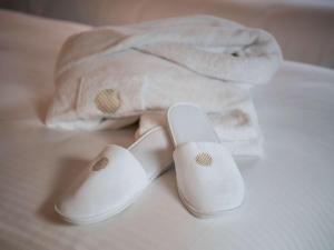 a pair of white slippers and a towel on a bed at Pullman Doha West Bay in Doha