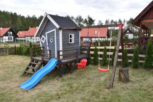 a playground with a slide and a play house at Domek w kratkę 56 in Załakowo
