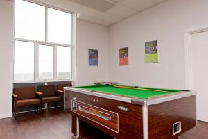 a pool table in a room with chairs and windows at YHA Manorbier in Tenby