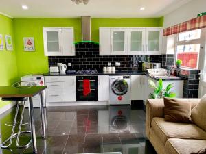 a kitchen with green walls and white appliances and a couch at 4 Bedrooms, 3 Baths, Full Kitchen and Lounge, Garden, Free Parking in London