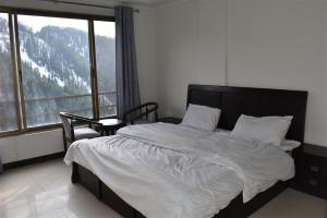 een slaapkamer met een bed en een groot raam bij Hotel Royal Inn in Murree