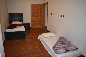 een slaapkamer met twee bedden en een houten vloer bij Hotel Royal Inn in Murree +6 foto's