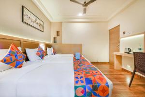 a bedroom with a large bed with colorful pillows at Nestlay Rooms Vanagaram in Chennai