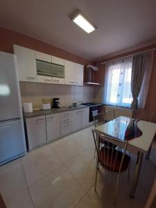 a kitchen with white cabinets and a table and a refrigerator at Casa Horea in Oradea