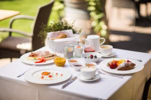 - une table avec des assiettes de petit-déjeuner dans l'établissement Boutique Hotel Zum Rosenbaum, à Nalles