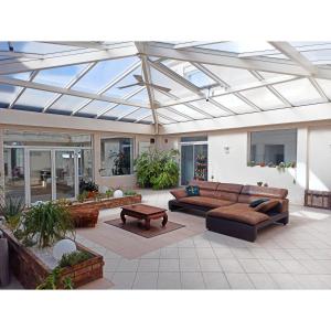 a living room with couches and a glass ceiling at Maison la grande serre in Blaslay