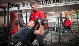 twee mannen in een sportschool met een man die gewichten optilt bij Maldron Hotel Portlaoise in Portlaoise